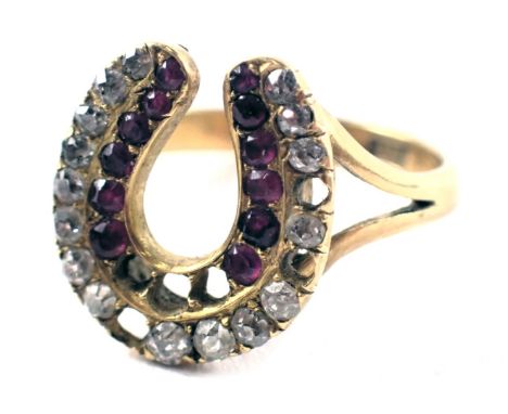 An Edwardian horseshoe ring, the two row horseshoe set with diamond and rubies, on V splayed shoulders, yellow metal stamped 