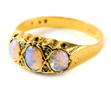 An opal dress ring, set with three oval opals and two tiny diamonds, in a raised claw setting on yellow metal band, stamped 1