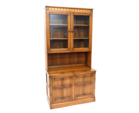 An Ercol mid coloured elm room unit or dresser, with two glazed doors, the base with two panelled doors, on a plinth. 