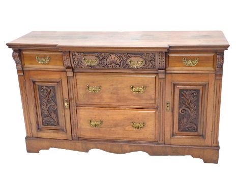 A late Victorian breakfront sideboard, the top with a moulded edge above an arrangement of five drawers and two carved panell