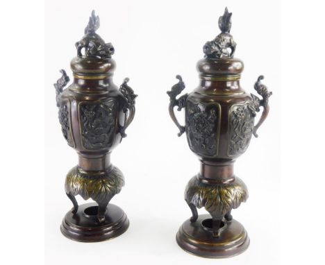 A pair of 19thC Japanese bronze vases and covers, with cast dog of fo finial, each with two ornate handles, the bodies decora