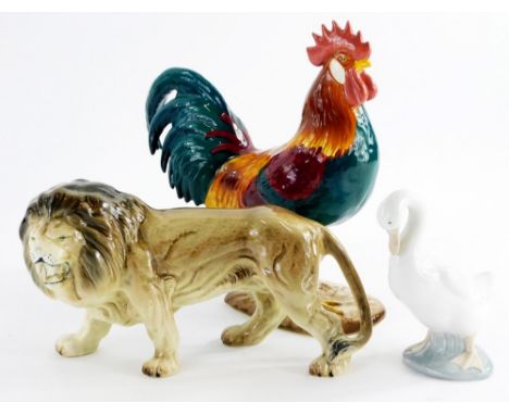 A Beswick figure of a leghorn cockerel, number 1892 and a ceramic lion figurine and a nao goose. (3)