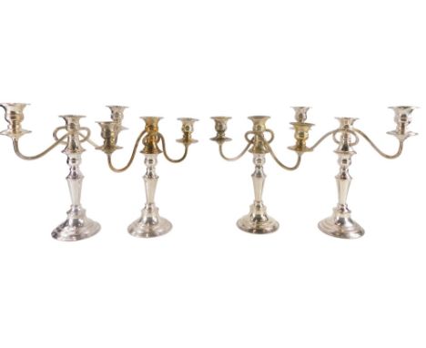 A set of four silver plated three branch candelabra, each with waisted stem and beaded borders, 30cm high, 30cm wide. 