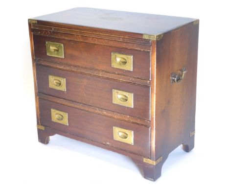 A small mahogany and brass bound campaign style chest of drawers, the top inset with an oval vacant cartouche, above three dr