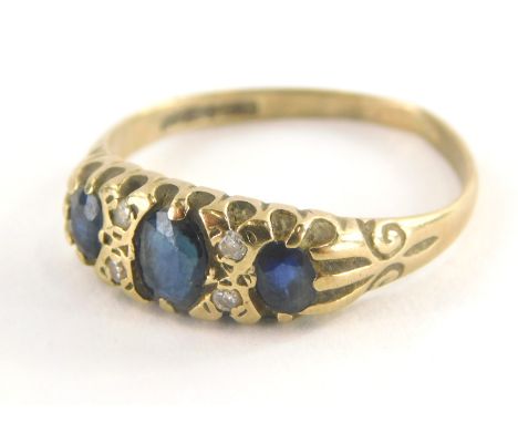 An 18ct gold sapphire and diamond gypsy ring, set with three oval cut sapphires and four tiny diamonds, on a misshapen band, 