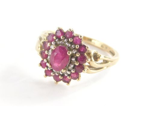 A 9ct gold cluster ring, with oval cut ruby in claw setting surrounded by cz stones and outer round brilliant cut rubies, on 