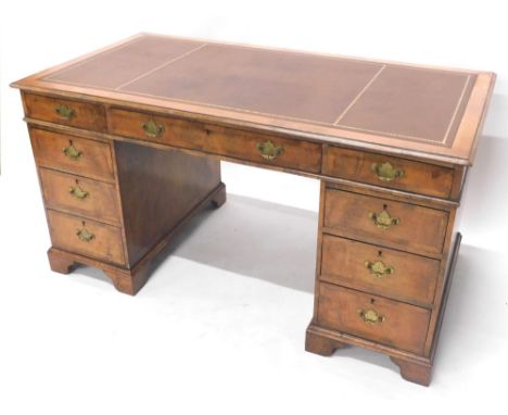 A walnut pedestal desk, the rectangular top with a brown gilt tooled leather inset, above nine crossbanded drawers, each with