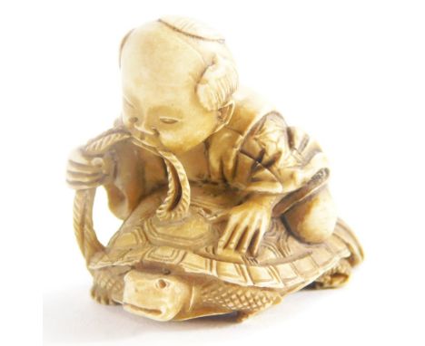 A Chinese carved netsuke, model in the form of a young boy seated on a turtle. (AF)