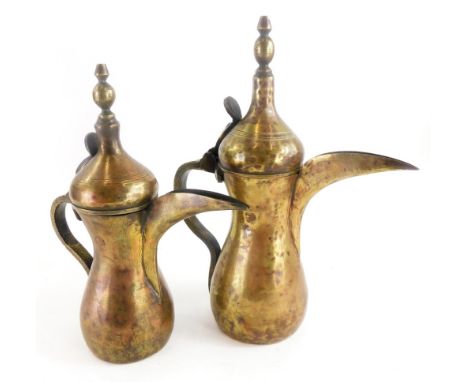 A pair of graduated Eastern metal ewers, with a shaped finial and long stem funnel, the largest 29cm high. 