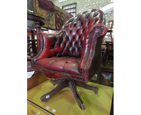 A claret/ox blood buttoned leather upholstered swivel office/desk chair with spoonback, swept and rolled arms raised on four 