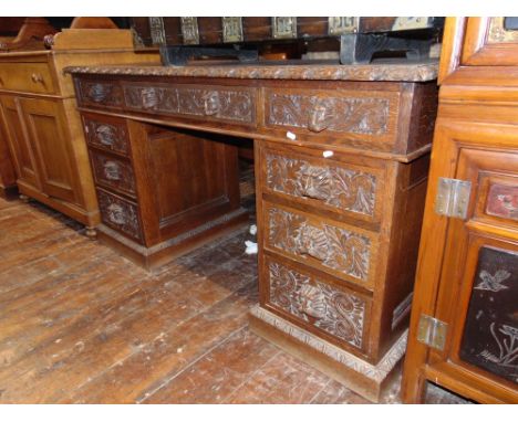 A Victorian oak pedestal desk of nine drawers with repeating carved detail and lion mask handles, with inset top, 150cm wide