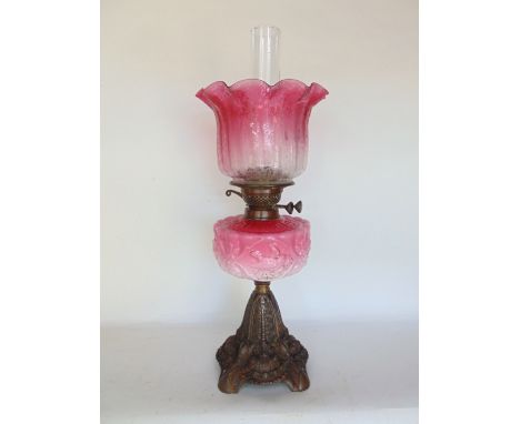 A late 19th century oil lamp with pink glass shade decorated with scrolled foliage and further pink and opaline glass reservo