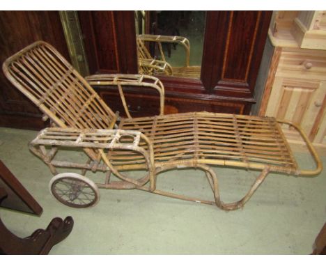 A vintage cane work lounger with wire spoke wheels and hard rubber tyres 