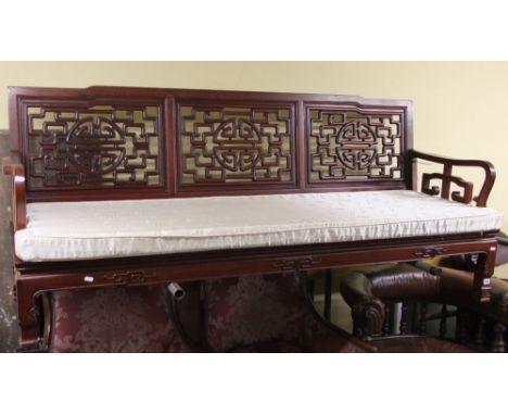 A Chinese hard wood framed sofa with pierced lattice work back and sides, square cut supports with squab cushion and applied 