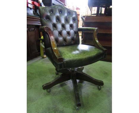 A reproduction swivel office/desk chair with green leather upholstered seat, button back and arms raised on four swept and mo