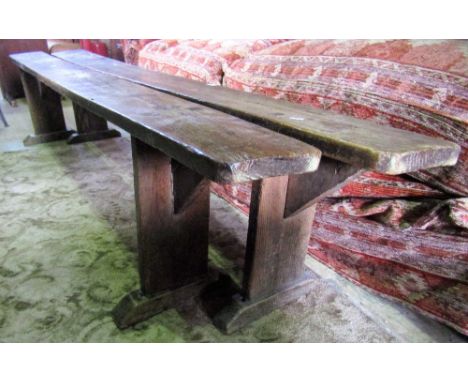 A pair of vintage pine refectory benches with plank seats raised on through jointed slab column supports and sledge feet, 7ft