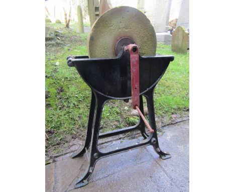 A vintage stone hand operated sharpening/grinding wheel with cast iron cradle and supports