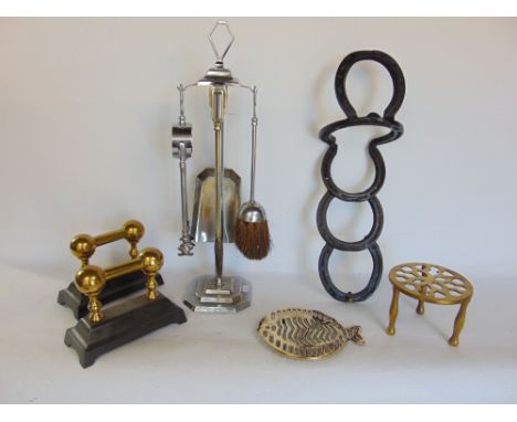 A mixed collection of metal ware to include two brass and cast iron fire dogs, two brass trivets, a novelty wall bracket made