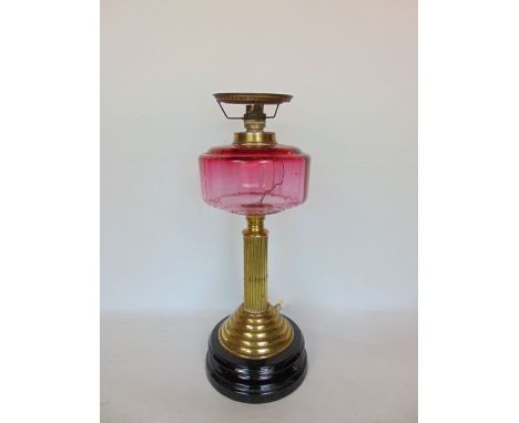 A 19th century brass oil lamp converted to electric, with cranberry glass reservoir upon a Corinthian column, 43cm high
