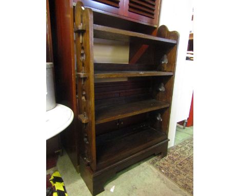 An oak freestanding open bookcase with pegged shelves and pierced trefoil detail and raised on bracket shaped supports