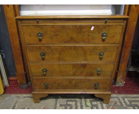 A walnut veneered bachelor's type chest of four long drawers with matched veneers beneath a brushing slide and raised on brac