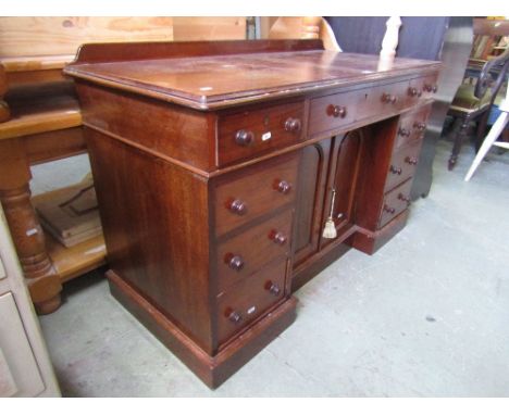 A Victorian mahogany inverted breakfront writing desk, fitted with nine drawers, the centre enclosed by a pair of arched cupb