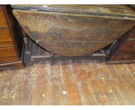 An antique oak gate leg dining table raised on eight turned supports, 115cm max length.