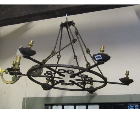 An iron work ceiling light of circular form with six fittings with arrow head and scrollwork detail supported by rope twist c