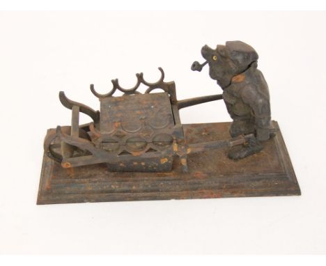 A 19th century cast iron inkwell and standish in the form of an amusing pipe smoking bear wheeling a barrow - with indistinct