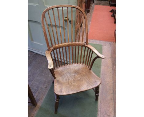 A Georgian Windsor comb back elbow chair with elm seat, fruit wood stick back, raised on turned supports and rails