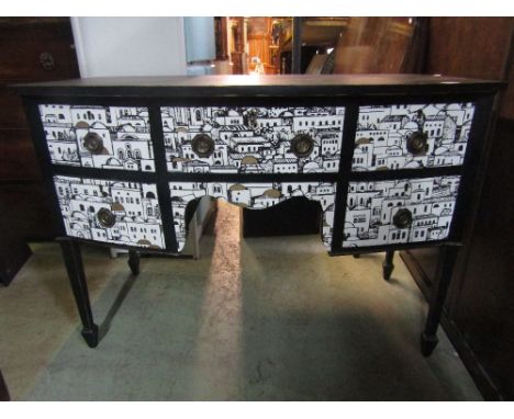 After Pierrot Fornasetti bow fronted sideboard/desk with city landscape overlay and ebonised frame upon square tapered legs, 