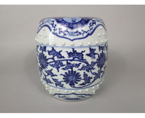 A small oriental ceramic stool with blue and white floral and trailing detail and moulded studded finish, 24cm high