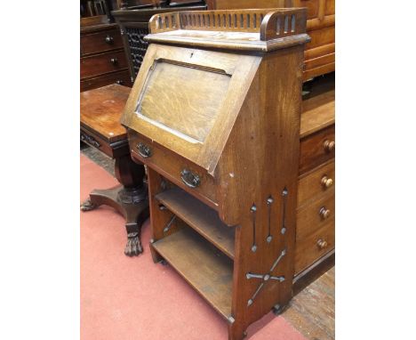 An art nouveau oak students desk, the fall front enclosing a very simply fitted interior over a frieze drawer and open shelf 