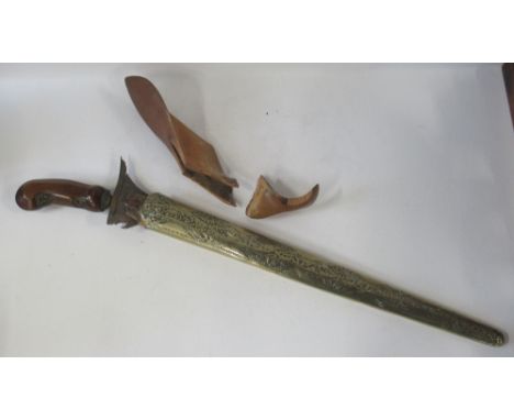 An Indonesian Kris dagger, with carved wooden handle, shaped blade, with brass covered scabbard
