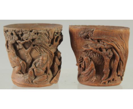 A SMALL PAIR OF CHINESE CARVED BAMBOO CUPS, relief carved with figures in a woodland scene, 5.5cm high.