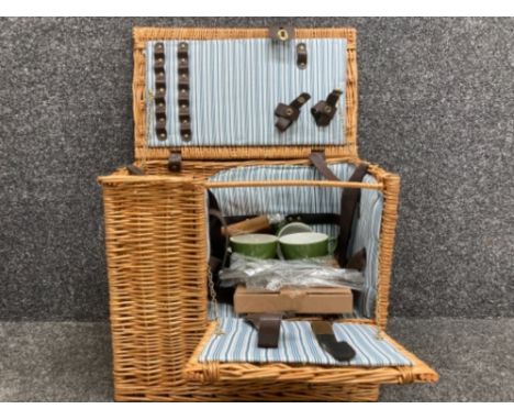 A vintage wicker picnic basket with contents