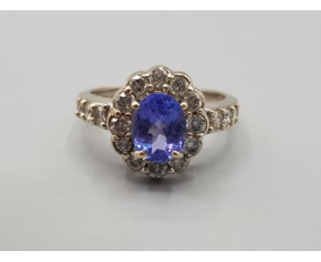 Ladies 14ct white gold tanzanite +diamond cluster ring, comprising of a oval shaped tanzanite stone set in the centre surroun