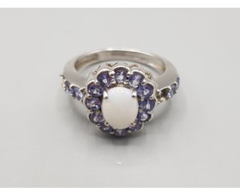 Ladies 9ct white gold opal + purple stone cluster ring, featuring a oval shaped oval set in the centre surrounded by 13 light