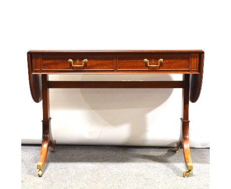 Pair of reproduction mahogany sofa tables, Regency style, satinwood crossbanding, two short drawers, brass caps and casters, 