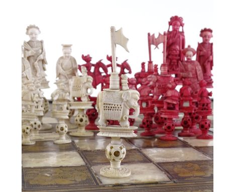 A 19th century Chinese carved red and white stained ivory chess set, with puzzle ball bases, King height 13cm, together with 