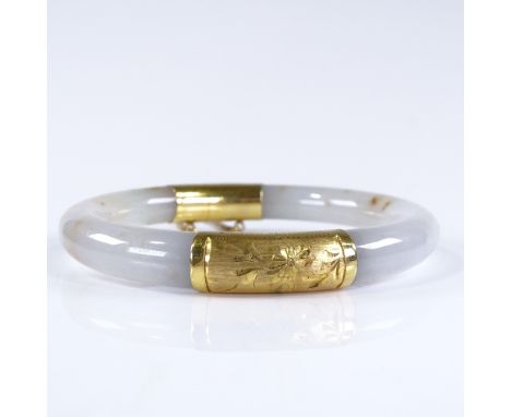 An Oriental jade hinged bangle, with unmarked gold mounts, internal diameter 55mm, 39.7g 