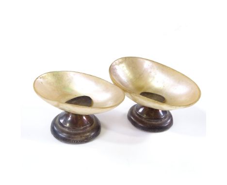 A pair of early 20th century mother-of-pearl shell table salts, on hallmarked silver bases, largest length 7cm 