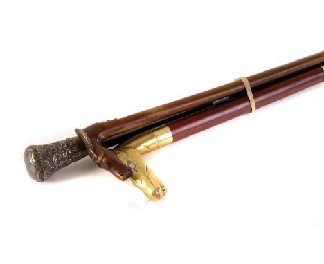 A group of three walking sticks, including a white metal topped example, a walking stick with brass horses head handle with s