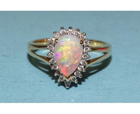 An opal and diamond cluster ring, claw set a tear drop opal within a surround of twenty brilliant cut diamond points in 18ct 