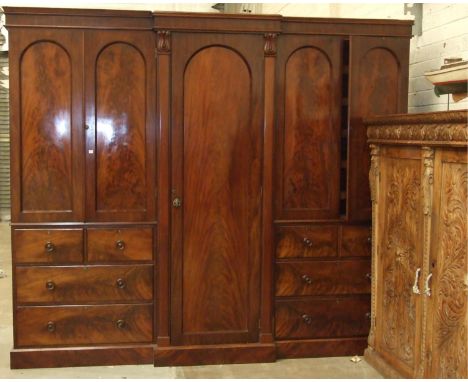 A very large Victorian mahogany breakfront wardrobe, the plain cornice above central hanging cupboard, two press cupboards an