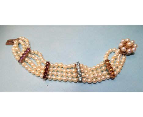 A bracelet of four strands of cultured pearls with four spacers set five round-cut citrines, blue zircons, garnets and amethy