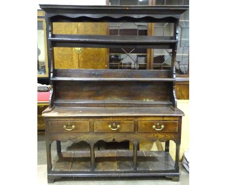 An 18th century oak dresser, the plate rack with moulded cornice above three shelves, the lower part fitted with three drawer