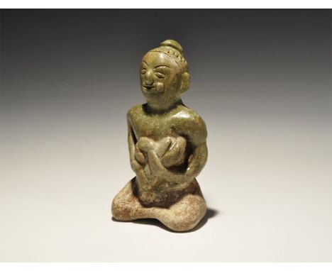 14th-16th century AD. A green-glazed ceramic figurine of a nursing mother sitting cross-legged cradling her child, hair drawn