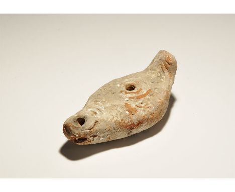 6th-9th century AD. A ceramic slipper-shaped lamp with concentric ribbing to the discus, long nozzle, lug handle to the rear,