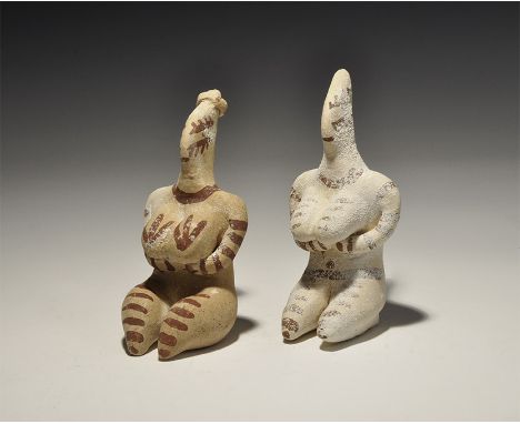 A pair of undated archaistic ceramic female figurines, each with arms clasped beneath the breasts, pinched face, painted brow
